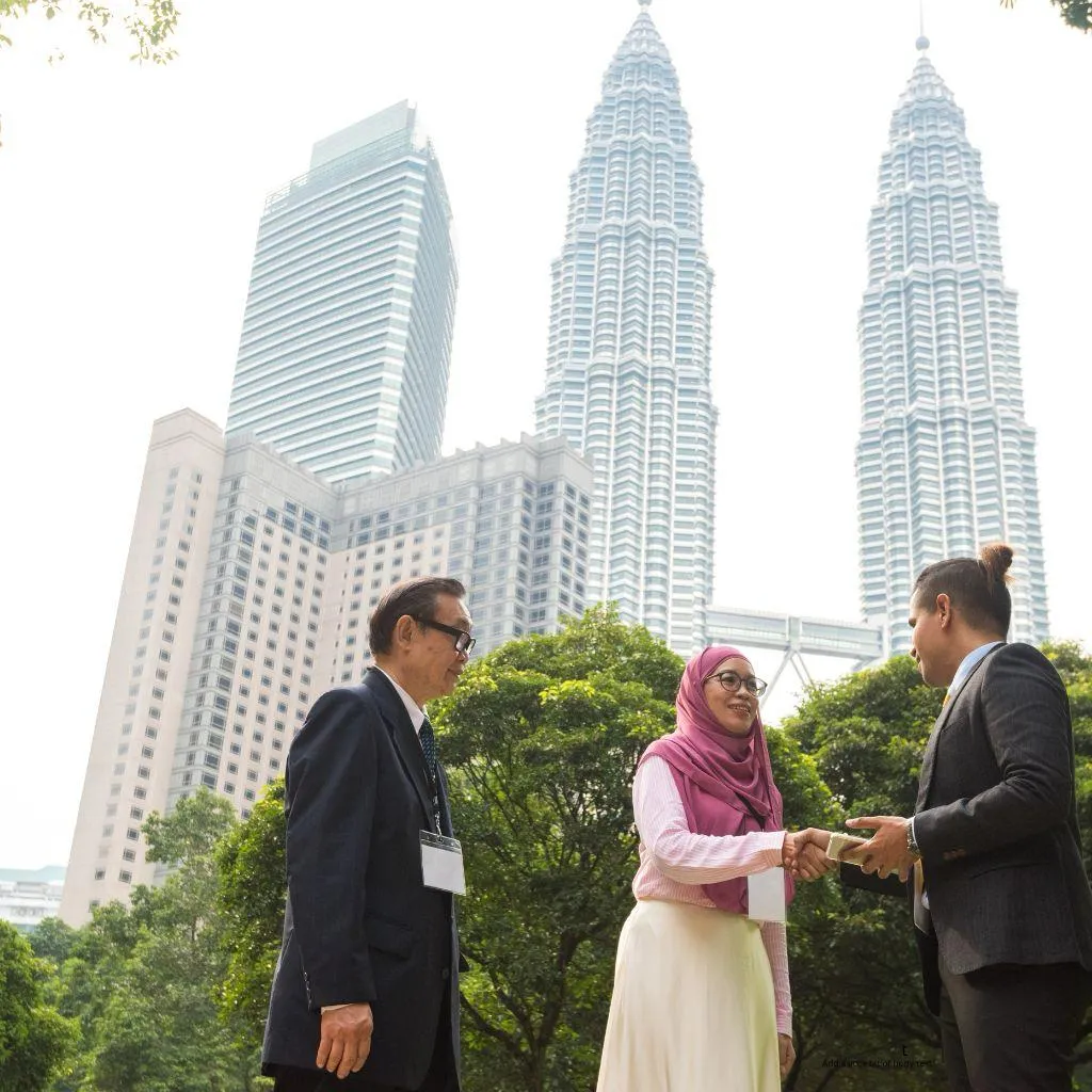 Business professionals shaking hands in Kuala Lumpur with the Petronas Towers in the background